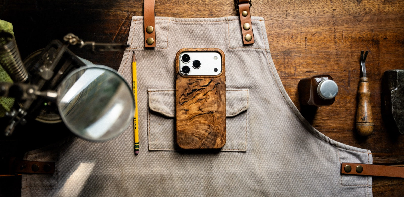 Solid wood phone case on a craft apron with woodworking tools